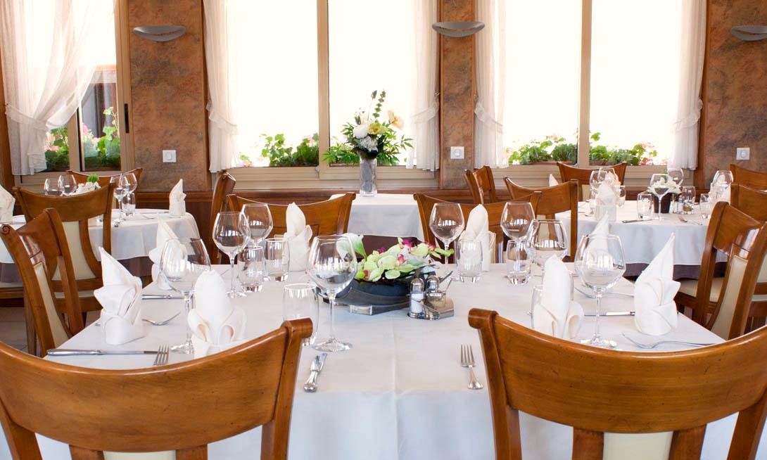 La salle du restaurant Au Bon Accueil, ses tables nappées de blanc et ses baies ouvertes sur le jardin